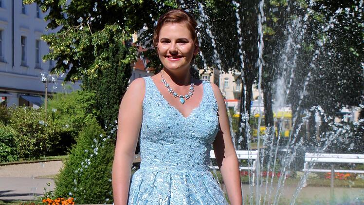 Quellenkönigin Ann-Sophie Brath trägt ein weit schwingendes, wasserblaues Kleid.