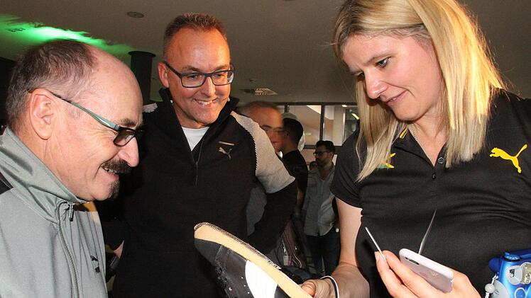 Puma-Ikone Helmut Fischer zeigt Sandra Kiriasis einen Schuh des Leichtathleten Klaus Wolfermann. Firmensprecher Ulf Santjer staunt über diesen Schatz zusammen mit der Trainerin.