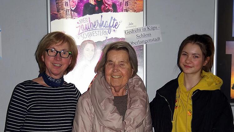 Kino-Betreiberin Brigitte Grober (von links) und Baronin Künsberg sowie Statistin Ida Wittmann vor dem Filmplakat, auf dem auch das Schloss Oberlangenstadt zu sehen ist.  Foto: Heike Schülein