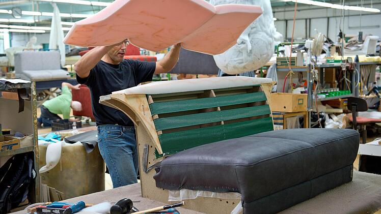 Ein Mitarbeiter fertigt in der Polsterei der Firma Ponsel in Weidhausen ein Ledersofa. Foto: David Ebener/dpa/Archiv