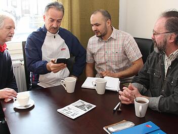 Ismael Mamo (Zweiter von links) zeigt auf dem Handy Bilder von seinem Sohn Serhat, Heiner Beyer, Abdellah el Haki und Bernhard Herrmann (von links) verstehen die Sorgen des 45-jährigen Familienvaters und möchten helfen. Foto:Matthias Beetz