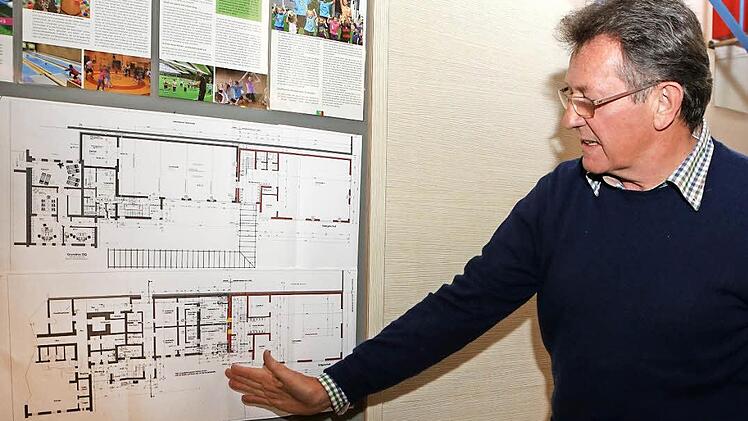 Vorsitzender Peter Röckelein vor den Bauplänen, die im Foyer ausgehängt sind.