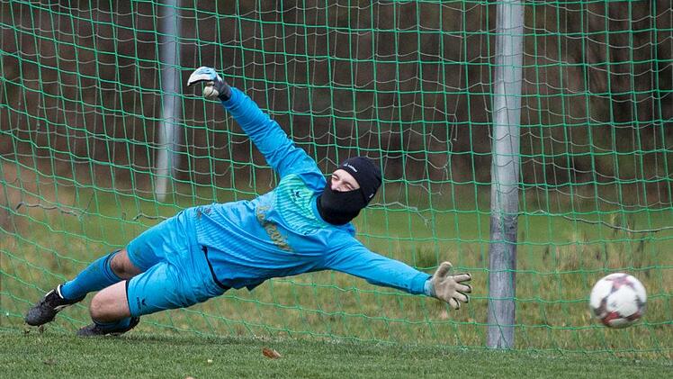 Mit Sturmhaube durch den November: Torwart Jan-Niclas Z&auml;nker von der SG Schm&ouml;lz/Theisenort II hat  gegen die SG Seibelsodrf die richtige Ecke erahnt, kann den Elfmeter von Daniel Hauck   aber nicht abwehren. Foto: Heinrich Wei&szlig;