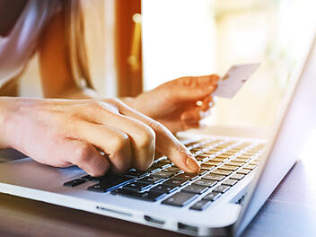 Frau beim Online-Shopping im Internet am Laptop mit Kreditkarte in der Hand.