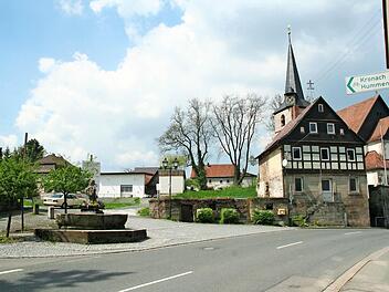 Blick auf die Dreieinigkeitskirche in Weißenbrunn und auf das davor stehende Lerners-Haus. Links davon soll das der Spitzhacke zum Opfer gefallene Schramms-Haus neu aufgebaut werden. Vorne der Dorfbrunnen "Jungferkättl"  Foto: Karl-Heinz Hofmann