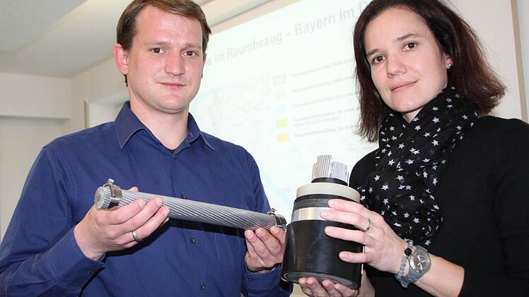 Tennet-Pressesprecher Markus Lieberknecht hält ein Stromkabel in der Hand, mit dem Gleichstrom von Wilster nach Grafenrheinfeld transportiert werden soll. Seine Kollegin Eva-Maria Schäffer zeigt ein Stück Erdkabel, mit dem der Gleichstrom auch unter der Erde befördert werden könnte. Foto: Paul Ziegler
