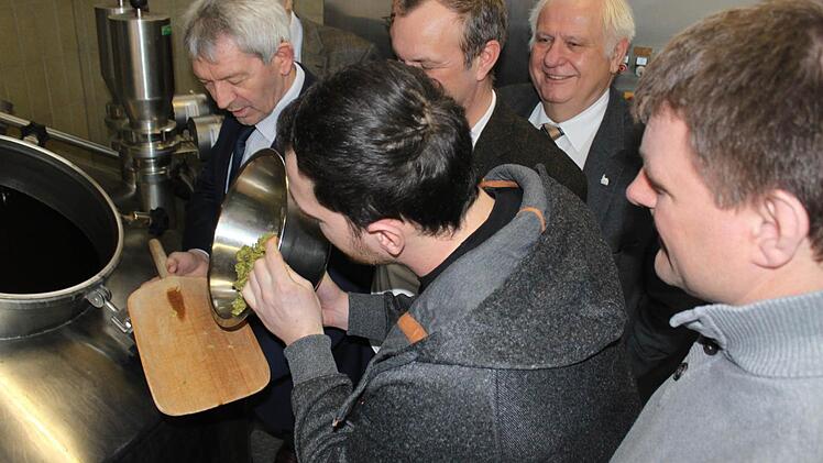 Damit der Hopfen im Malz nicht verloren geht, erhält Landrat Johann Kalb (links) beim Würzen den Suds Nachschub von den Braumeistern David Hertl (mit Hopfenschale), Jörg Binkert (halb verdeckt) und Christian Sauer (rechts).