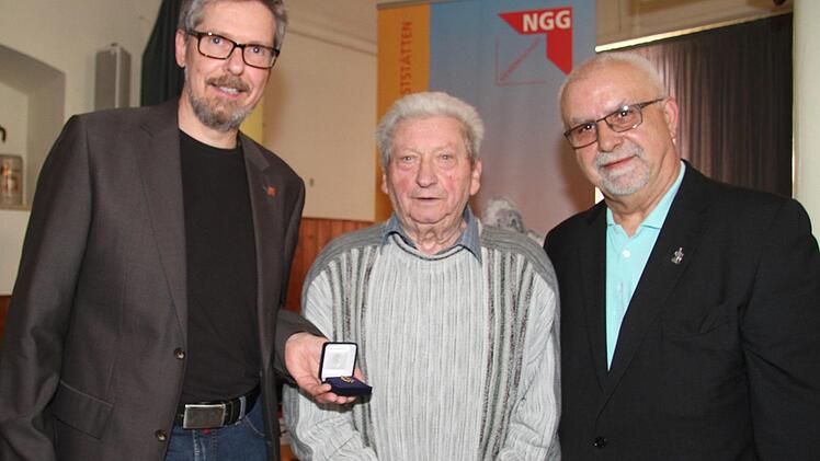 Mit einem Lächeln nimmt der 85-jährige Kurt Grampp die Auszeichnung aus den Händen des Ortsvorsitzenden Hans-Georg Prehmus (rechts) und des Geschäftsführers Michael Grundl entgegen. Foto: Sonny Adam