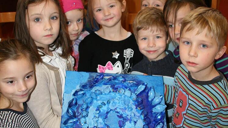 Die grünen Kinder - also die größten im Kindergarten - zeigen stolz das Werk der kleinsten: Die Küken haben aus Nudeln ein blaues Farbbild gestaltet. Foto: Daniela Röllinger