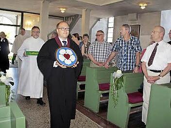 Die gemalte Schieferplatte mit der Lutherrose wird von Prädikant Thomas Rebhan beim Einzug zum ökumenischen Gottesdienst in die evangelische Kirche in Ludwigsstadt getragen. Foto: Simone Büttner