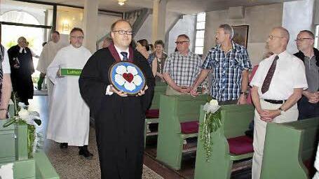 Die gemalte Schieferplatte mit der Lutherrose wird von Prädikant Thomas Rebhan beim Einzug zum ökumenischen Gottesdienst in die evangelische Kirche in Ludwigsstadt getragen. Foto: Simone Büttner