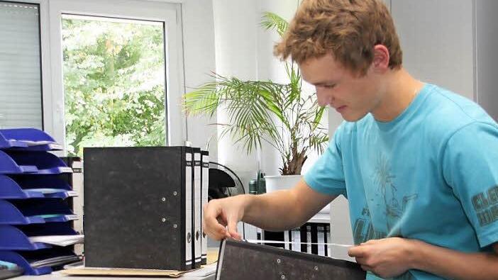 Johannes Herold (17) beklebt während seiner Ferienjobs unter anderem Ordner und sortiert diese.