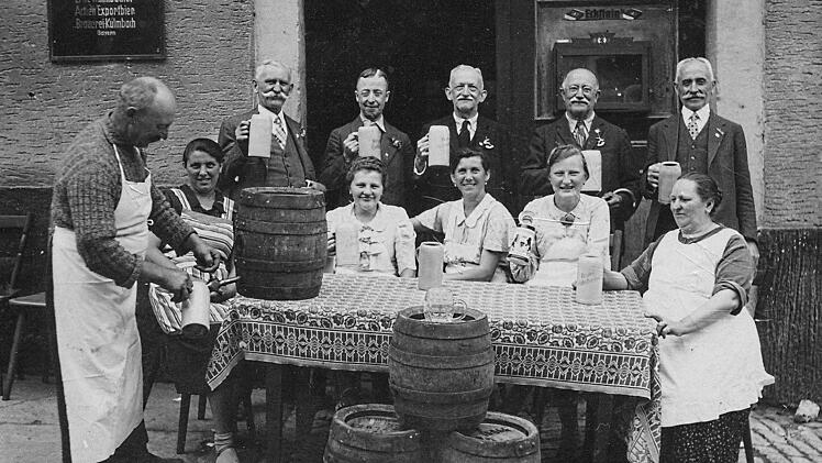 Der Wirt Hans Mattes (links) und die Wirtin Maria (rechts sitzend) vor ihrer Gaststätte mit Gästen bei einer Feier. Die Frauen von links sind Meta Pöhlein von gegenüber, die Wirtstochter Betty Mattes (1921 - 2001), Barbara Römmel, geborene Siegel, Antonie Harbauer, geborene Köhler. Die Namen der Herren sind bislang unbekannt.