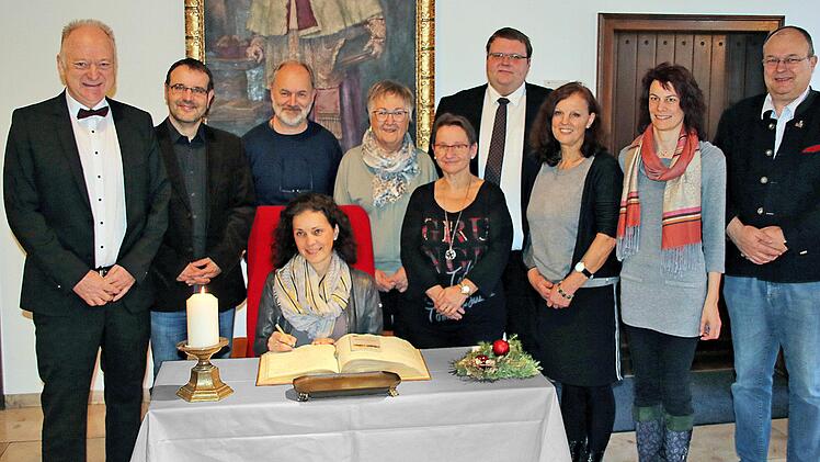 Beim Eintrag ins Goldene Buch (von links): Bürgermeister Helmut Blank (CSU), Oliver  Schikora, Josef Wilz (hinten, stehend), Christine Schikora (vorn, sitzend),  Magda Michel, Kulturreferentin Michaela Wedemann (CSU), 2. Bürgermeister  Andreas Trägner (Freie Wähler), Carmen Schlott, Christine Tapken und 3.  Bürgermeister Axel Knauff. Dieter Britz