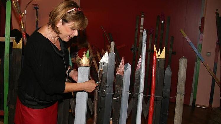 Die Zaunlatten sehen nicht nur schmuck aus, sondern sie sind Kunst: Die goldenen Aufsetzer symbolisieren den Prinz, der Schneewittchen schließlich erlöst - und die Zwergenkappen sind natürlich sieben.