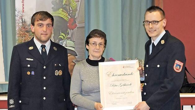 Die Vorsitzenden des Feuerwehrvereins, Rolf Bergmann (rechts) und Sebastian Bail (links), &uuml;berreichen Rita Gebhardt die Urkunde zur Ehrenvorsitzenden.  Foto: Feuerwehr/Marcus Weise