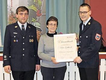 Die Vorsitzenden des Feuerwehrvereins, Rolf Bergmann (rechts) und Sebastian Bail (links), &uuml;berreichen Rita Gebhardt die Urkunde zur Ehrenvorsitzenden.  Foto: Feuerwehr/Marcus Weise