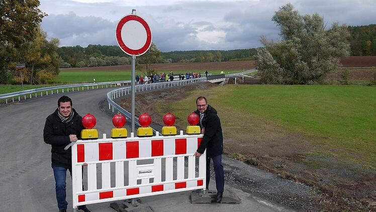 Weg das Ding: Maximilian Neeb und Sebastian Straubel (rechts) nehmen sich höchstpersönlich der Baustellenabsperrung für die neue Brücke über die Rodach (im Hintergrund) an.- Foto: Berthold Köhler