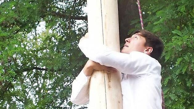 Auch heute noch ein beliebter Brauch auf Volksfesten: Beim Kronenfest im Weihersbach muss ein entrindeter Baum erklommen werden - ohne Schleifpapier, aber mit Stiefeln. Foto: Manfred Welker