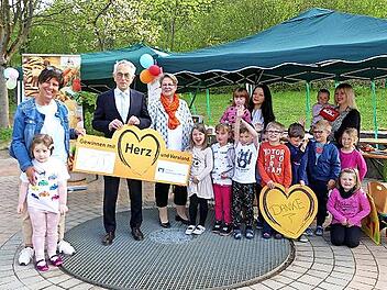 Die Kinder der Fölschnitzer Kita freuen sich mit (von links) ihrer Leiterin Brigitte Sintenis-Herr, Bereichsdirektor Gerhard Zettel, Elke Wuthe (Die Kita) und den Kita-Mitarbeiterinnen Stefanie Seifert und Jacqueline Gründonner. Im Hintergrund der Frühstücks-Aktionsstand.