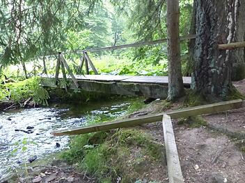 Mit brachialer Gewalt ist das Geländer der Rehbachbrücke an der Hübnersmühle abgerissen worden. Es muss jetzt von den ehrenamtlichen Kräften des Frankenwaldvereines Grafengehaig kurzfristig wieder repariert werden.  Foto: Klaus-Peter Wulf