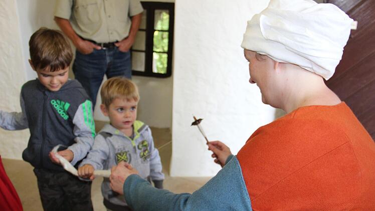 Jakob und Luis Thaler sind mit ihren Großeltern auf der Burg Zwernitz und ganz begeistert von der weichen Wolle, aus der Nadine Zanner dünne Fäden spinnt. Foto: Katharina Müller-Sanke