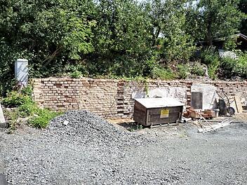 Noch ist unklar, wie die bestehende Backsteinmauer (unser Bild) hinter dem Rathaus gesichert wird. Favorisiert wird eine Betonmauer aus L-Steinen. Denkbar ist aber auch eine Gabionenwand. Die Kostenfrage wird am Ende für die Entscheidung wichtig sein, und die treffen die Mitglieder des Bauausschusses nach Vorlage der Angebote. Foto: Werner Reißaus
