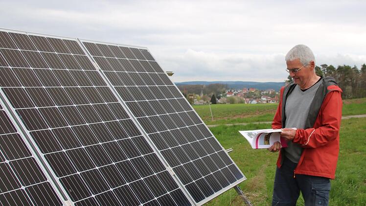 Claus Schmitt blättert in dem über 30 Jahre alten Arbeitspapier  des Kuratoriums für Technik und Bauwesen in der Landwirtschaft. So ist er auf Photovoltaikanlagen aufmerksam geworden. Seine Anlage war eine der ersten in Unterfranken. Foto: Thomas ...