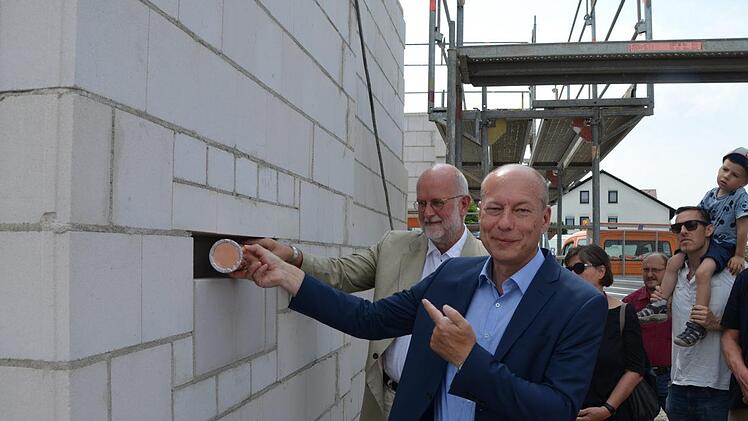 Die Kapsel wurde von Bürgermeister Michael Karmann (im Vordergrund) zusammen mit Christoph Gatz in einer Wand in der Kindertagesstätte versenkt.Andrea Spörlein