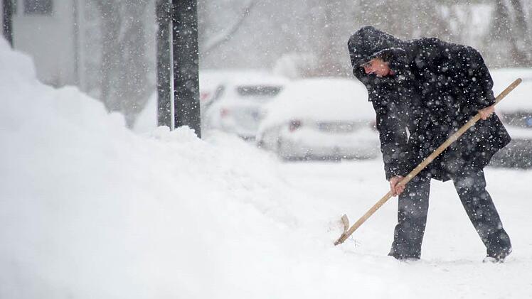 Der Neuschnee lässt sich leicht mit einem Fächerbesen zur Seite kehren. Symbolbild: Tobias Hase/dpa