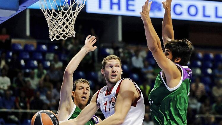 Janis Strelnieks (mit Ball) sucht gegen Malagas Riesen Fran Vazques (l.) und Daniel Diaz einen freien Mitspieler. Foto: Jorge Zapata/dpa