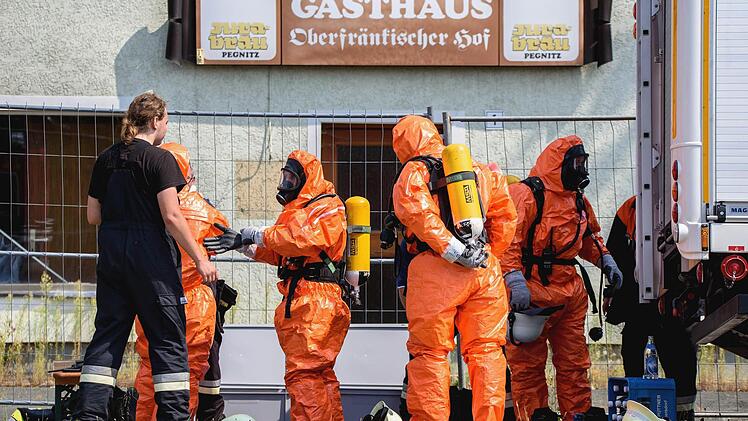 Einsatzkräfte der Feuerwehr ziehen sich am 11.08.2015 in Engelmannsreuth (Bayern) Ganzkörper-Schutzanzüge an. Bei Engelmannsreuth ist ein F-16 Kampfjet der US-Streitkräfte abgestürzt. Foto: Nicolas Armer/dpa