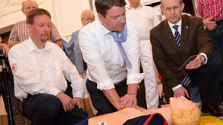 Unter fachkundiger Leitung "reanimiert" hier MdL Sandro Kirchner eine Übungspuppe. Ihm stehen Rotkreuz-Ausbilder Thomas Menz (links) und BRK-Kreisvorsitzender Bad Kissingen, Dr. Alexander Siebel (rechts) zur Seite. Foto: Peter Rauch