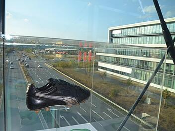 Ein Lederschuh von Lothar Matthäus schwebt über Herzogenaurach: Der Weltfußballer ist Teil der Ausstellung auf der Brücke hoch über der Nordumgehung. Zeitzeugen von 70 Jahren Puma sollen später auch der Öffentlichkeit zugänglich gemacht werden.  Fotos: Bernhard Panzer