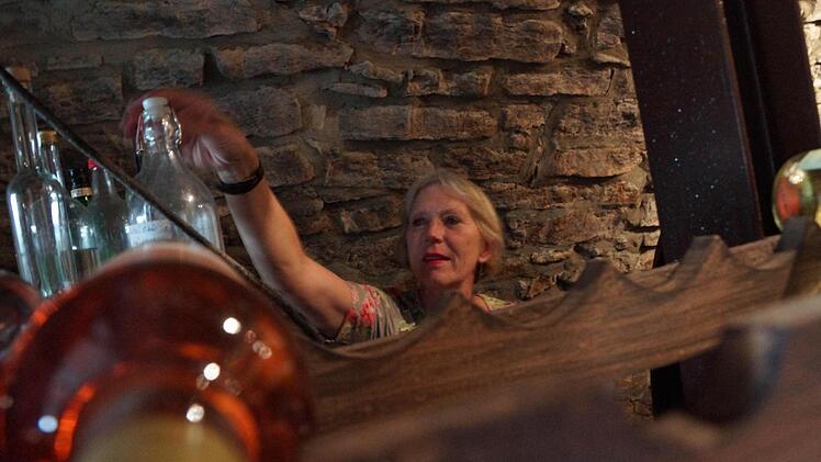 Regine Kuhn holt einen Schnaps vom Regal.