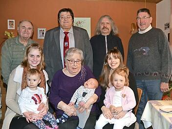Theresia Kaim mit Urenkel Philipp, dem jüngsten Sprössling der Familie, im Kreise ihrer Familie. Mit im Bild (stehend von rechts) Helmut Müller, Pater Helmut Haagen und Zweiter Bürgermeister Wolfgang Förtsch.  Foto: K.- H. Hofmann