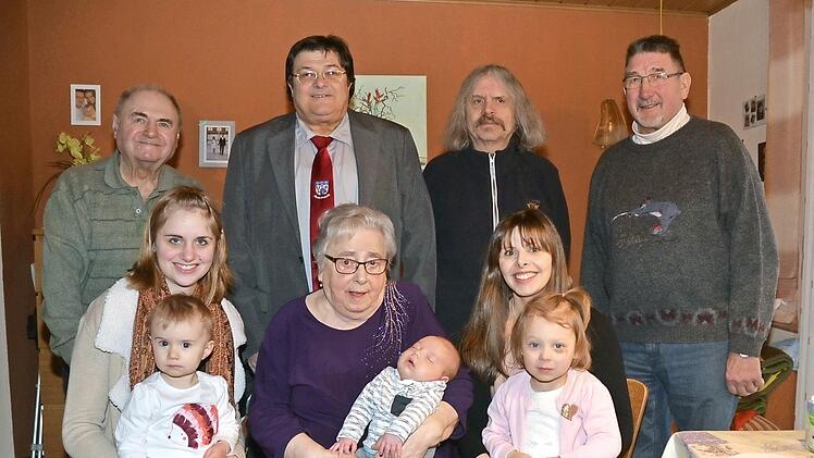 Theresia Kaim mit Urenkel Philipp, dem jüngsten Sprössling der Familie, im Kreise ihrer Familie. Mit im Bild (stehend von rechts) Helmut Müller, Pater Helmut Haagen und Zweiter Bürgermeister Wolfgang Förtsch.  Foto: K.- H. Hofmann