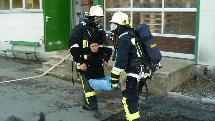 Mit schwerem Atemschutz ausgerüstet bergen Feuerwehrleute "verletzte" Recaro-Mitarbeiter aus dem Gebäude. Fotos: Klaus-Peter Wulf