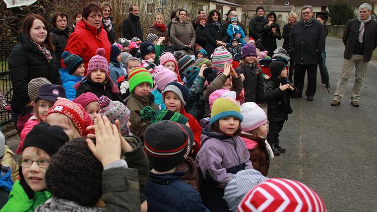 Gespannt verfolgen die Kinder sowie Pfarrer Rudolf Scharf (Zweiter von rechts) und Bürgermeister Berhard Storath (rechts) die kleine Zeremonie mit dem Richtspruch des Zimmermanns.