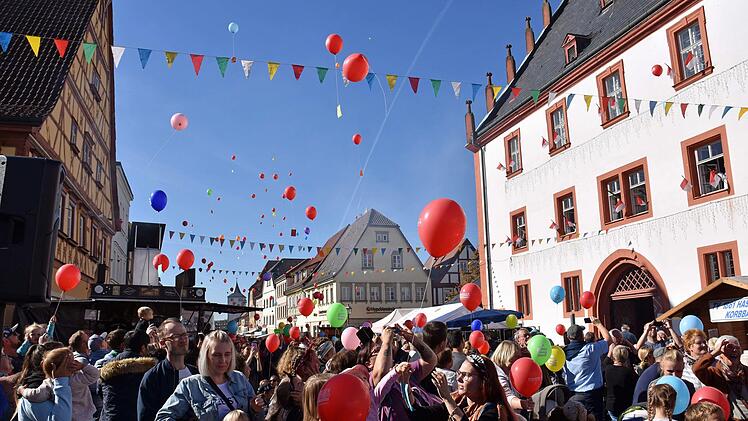 Luftballons steigen beim Straßenfest in den Himmel.