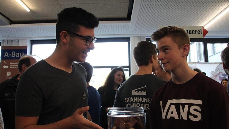 Lehrling Dogan Apari vom  Backmittelhersteller Ireks erläutert Tom Mücke, der sich für den Beruf  Fachkraft für Lebensmitteltechnik interessiert, anhand von Cookies, was in  einer Backmischung vorhanden ist. Foto: Stephan Stöckel