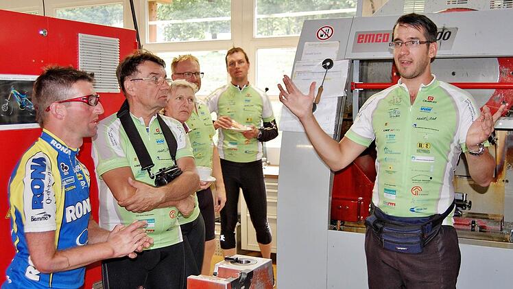 Radler Thomas Gensler (30) erklärt Teilnehmern der Reha-Radtour seinen Arbeitsplatz an der computergesteuerten CNC-Fräsmaschine in der Nüdlinger Lebenshilfe-Werkstatt. Foto: Sigismund von Dobschütz