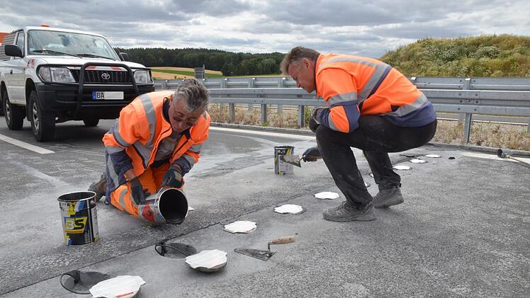 Arbeiter gießen die Unterflurleuchten in die Fahrbahn der Autobahnanschlussstelle Ebersdorf ein. Fotos: Rainer Lutz