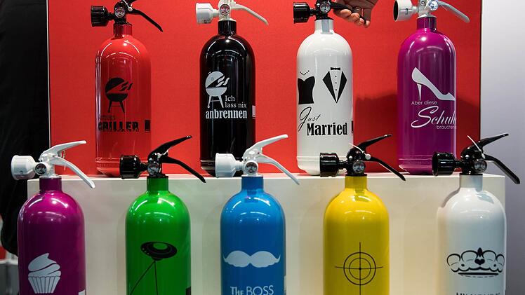 Feuerlöscher sollen auch gut aussehen - hier sind welche mit unterschiedlichen Aufdrucken während der Brandschutzmesse "FeuerTrutz" in Nürnberg zu sehen.  Foto: Daniel Karmann/dpa