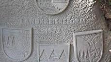 Der Gedenkstein mit dem Landkreiswappen (oben) und den Wappen der früheren Kreise (von links) Haßfurt, Hofheim und Ebern.