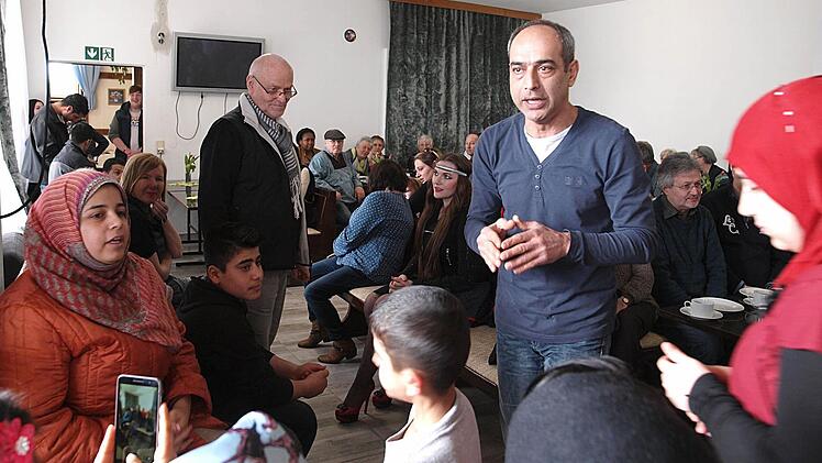 Renza (Bildmitte), vor mehr als 30 Jahren aus dem Iran nach Deutschland gekommen, überwindet als Übersetzer die Sprachbarriere am Wochenende im früheren Grenzgasthof. Das Interesse und auch die Neugier der Einwohner von Fürth amBerg an den 39 Flüchtlingen ist groß. Foto: Christoph Winter