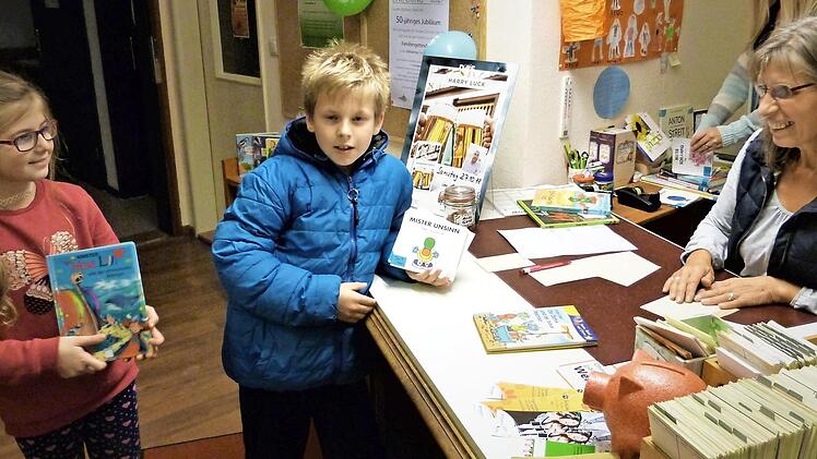 Mirell und Jason sind gerade dabei, ein Kinderbuch auszuleihen, rechts Silvia Henke. Foto: Werner Reißaus