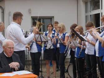 Pfarrer Johann Baptist Schmitt (am Tisch) und Pater Placidus Berger (neben dem Dirigenten) hören dem Musikverein zu, der ihnen zu Ehren aufspielte. Foto: Johannes Michel