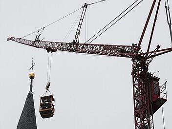 Am Haken des Auslegers: Der Kranführer fährt die beiden Dachdecker in der Arbeitsbühne zum Südturm hoch samt Arbeitsgeräten und Material. Dort haben sie gearbeitet.  Fotos: Rainer von Andrian-Werburg/Dachdecker Collins/Ruprecht