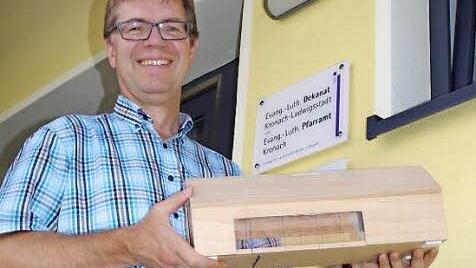 Pfarrer Martin Gundermann freut sich auf die baldige Realisierung des Gemeindehauses. Das Bild zeigt ihm mit einem Model, das Adolf Engel nach Originalmaßstab nachgebaut hat.  Foto: Heike Schülein